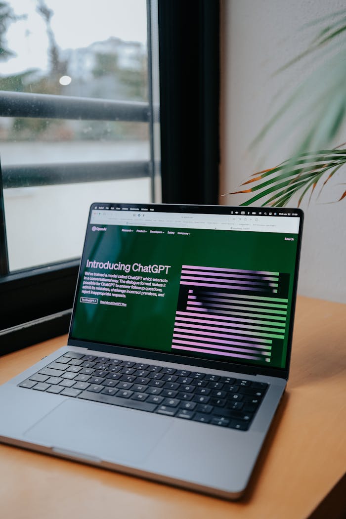 Laptop on a desk showing ChatGPT interface next to a window, symbolizing modern technology.